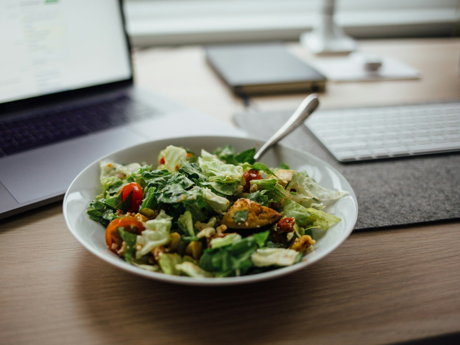 Ofis masasında dizüstü bilgisayarın yanında salata kasesi